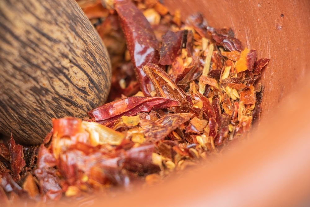 Dried red chiles crushed in a terracotta mortar with a wooden pestle