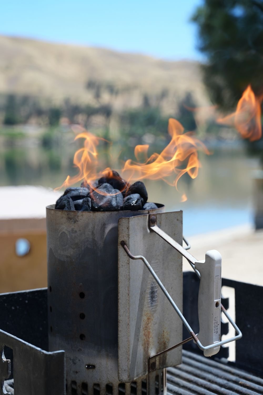 Charcoal chimney starter with flames rising over the coals