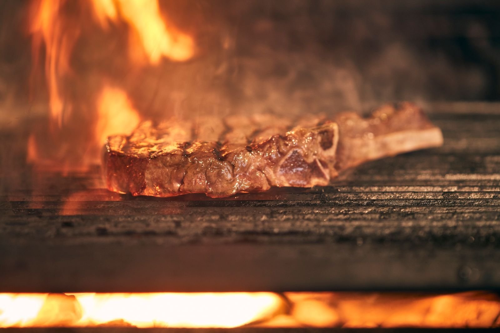 Bone-in tomahawk steak cooking over a live charcoal fire