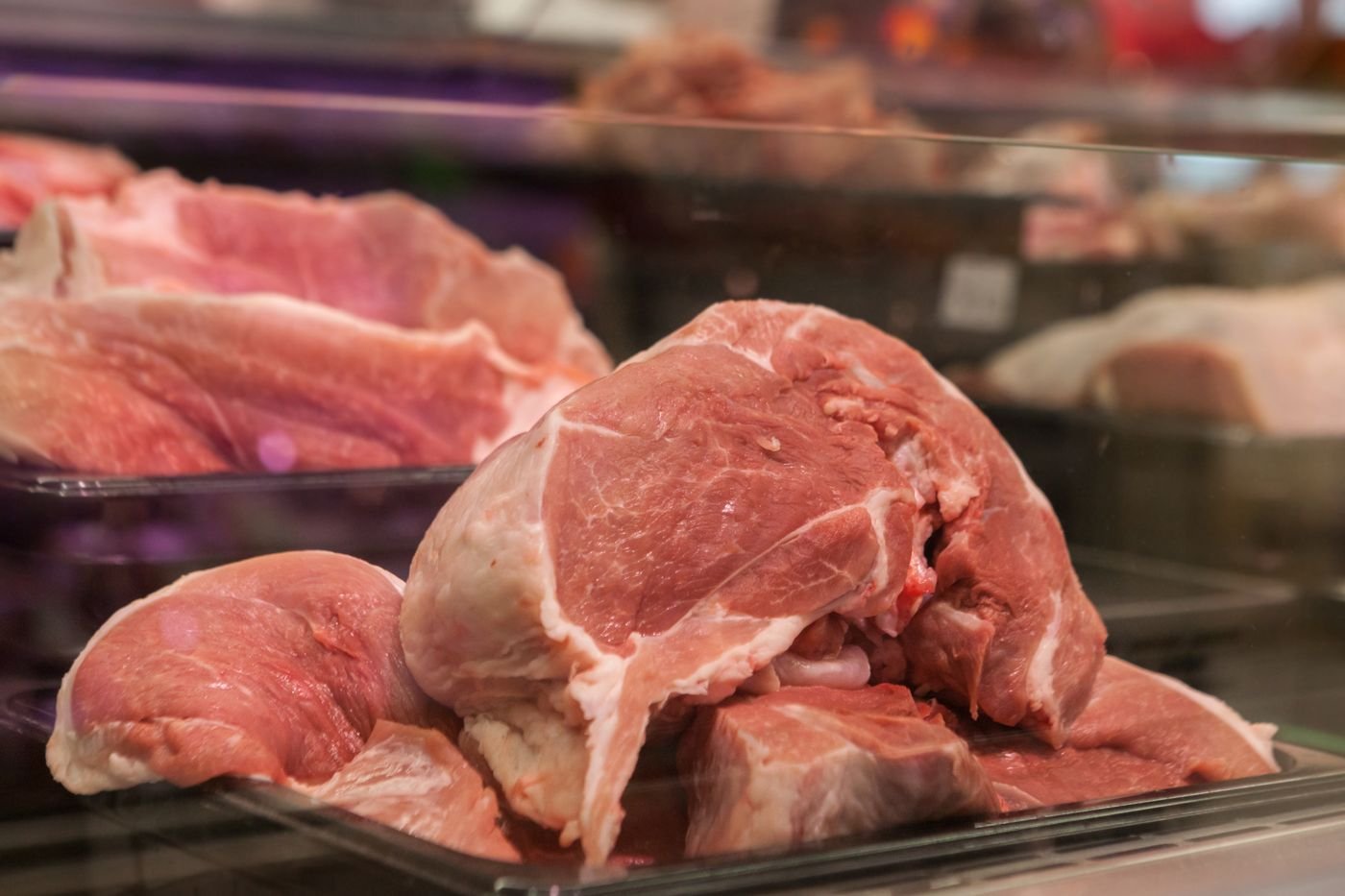 Fresh cuts of pork and beef inside a butcher counter display case