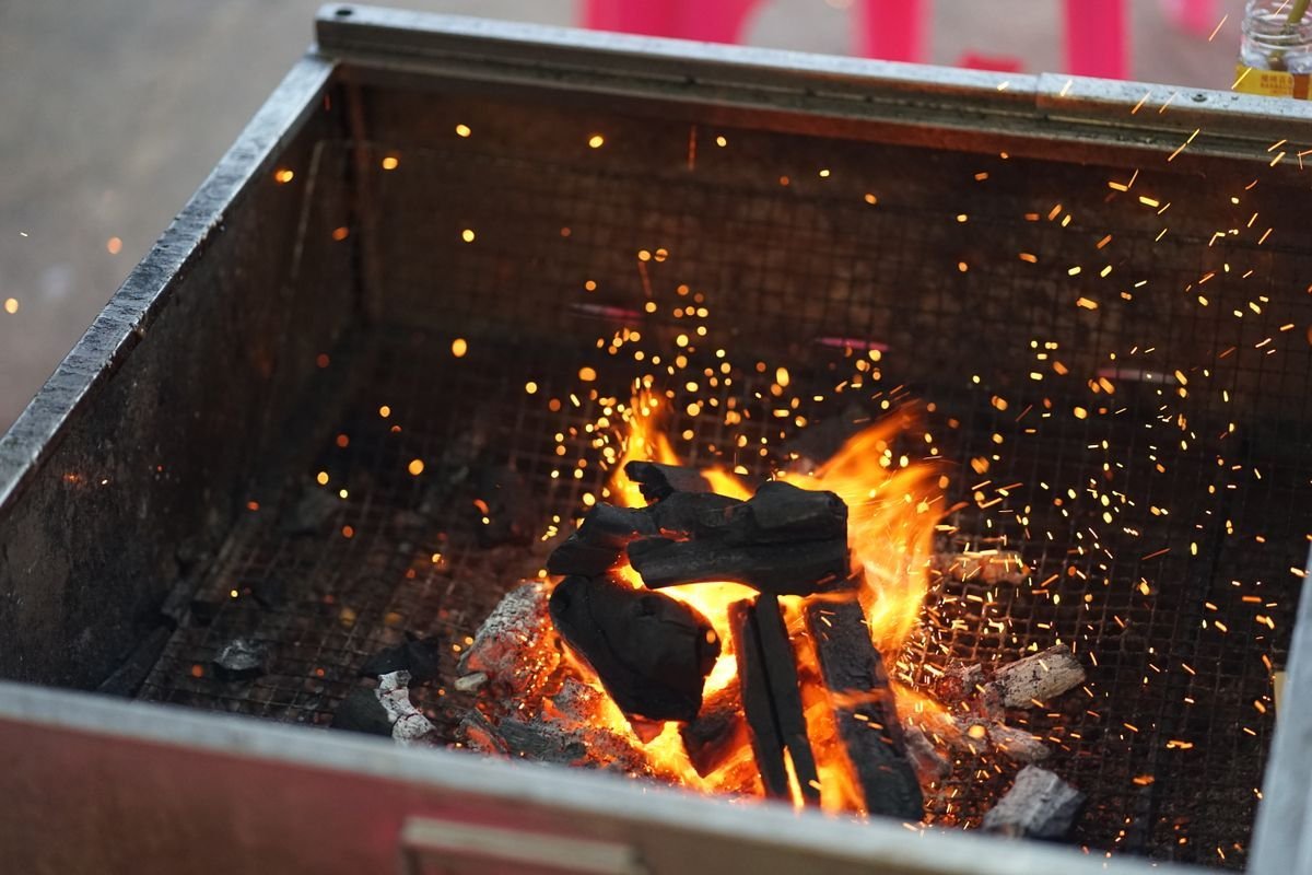Glowing charcoal throwing bright sparks inside a steel grill box